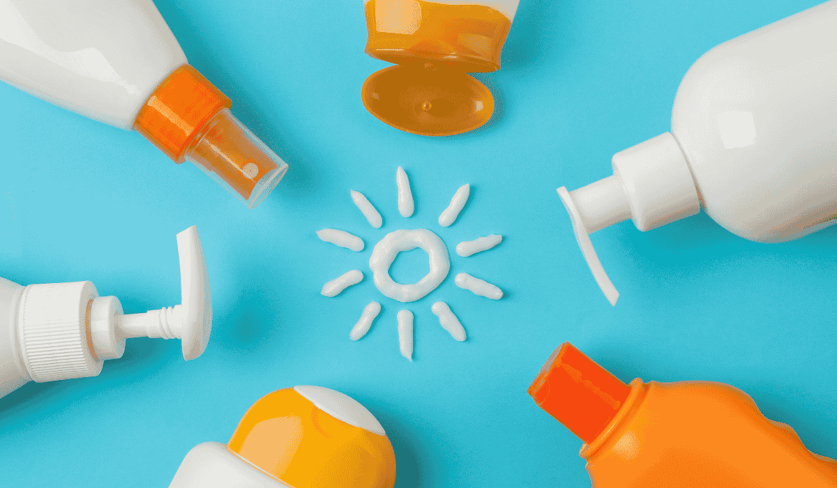 Different bottles of sunscreen formats: sprays, lotions, creams on a blue background